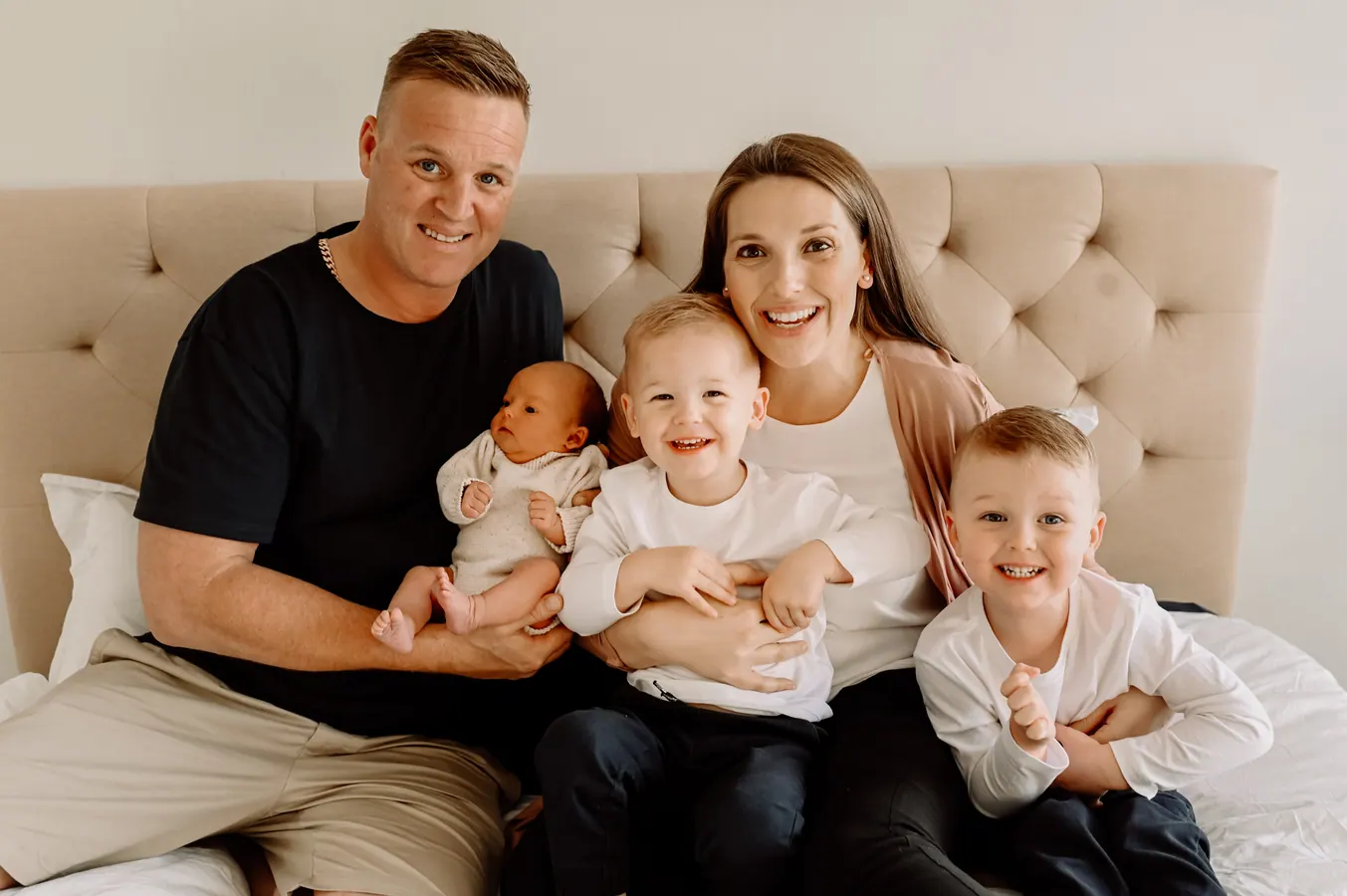 Courtney, her husband and their three boys on a bed, the youngest a newborn